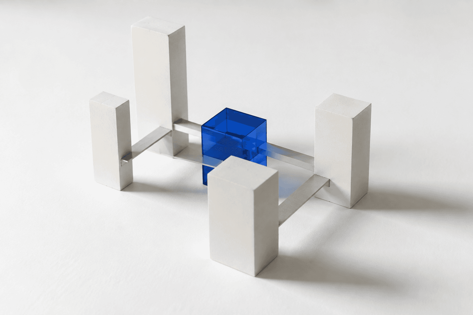 A physical architectural model of separate blocks joined by small bridges around one blue glass block