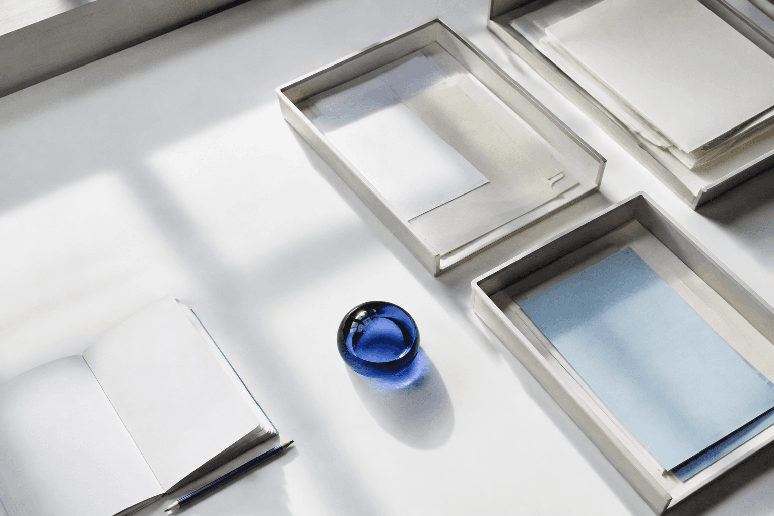 An editorial still life of document trays, paper folders and a blue glass paperweight