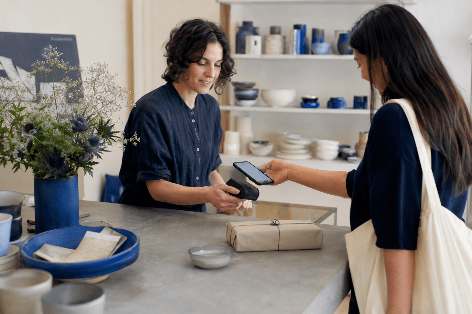 Illustrative customer paying by phone at an independent design-store counter