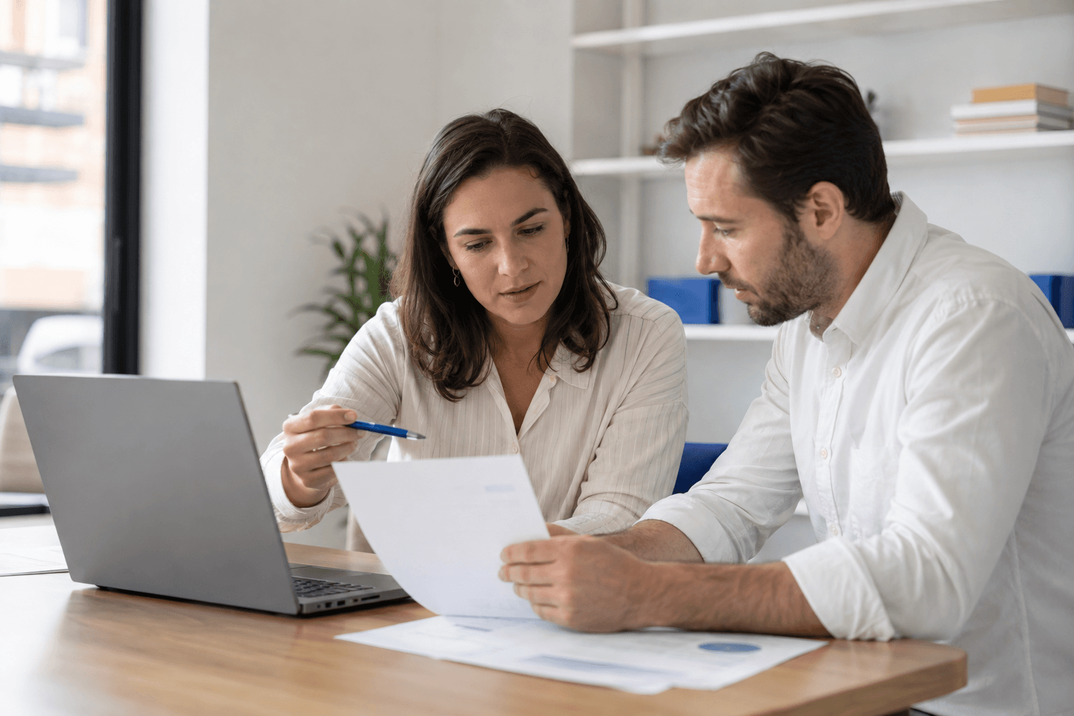 Illustrative finance colleagues reviewing a laptop and invoice documents together